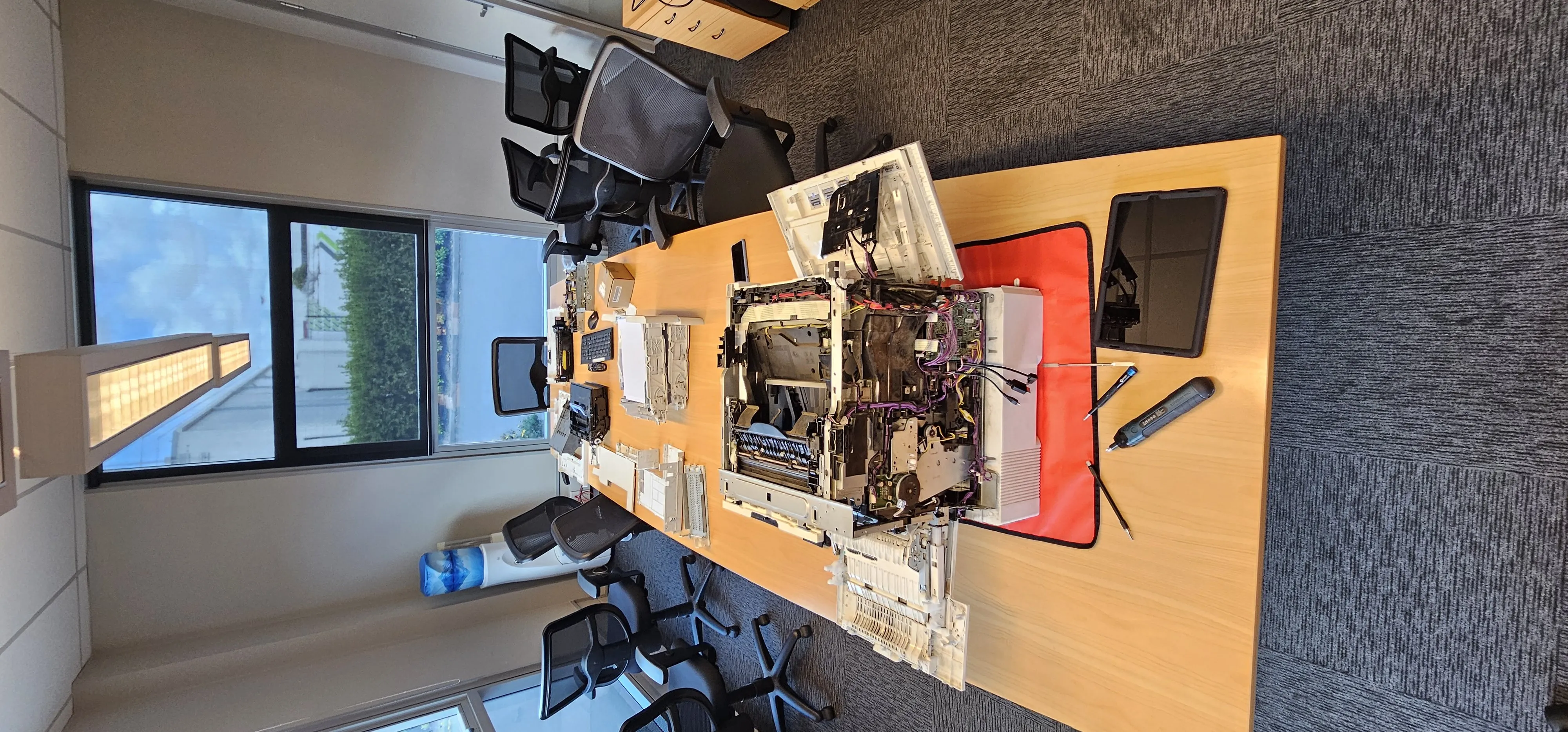 Large printer fully disassembled on a table for repair